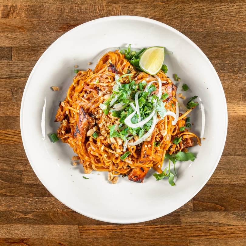 A plate of Mexiyaki's Pad Thai noodles, garnished with lime, cilantro, and crushed peanuts.