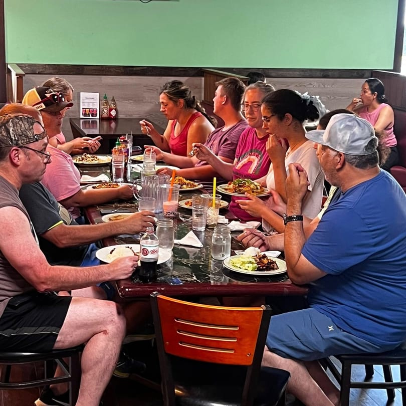 Diners enjoying Asian cuisine at a long table in Mexiyaki restaurant.