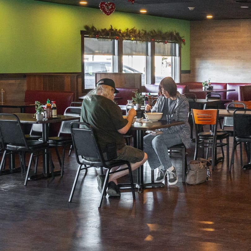 Two customers enjoying Asian cuisine at a table in Mexiyaki, with festive decorations in the background.